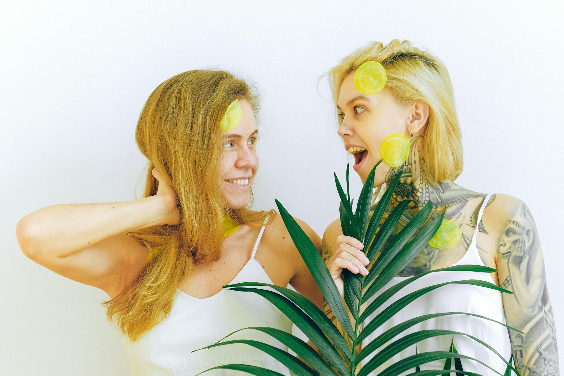 Two women laughing together with tropical plants, expressing joy and connection