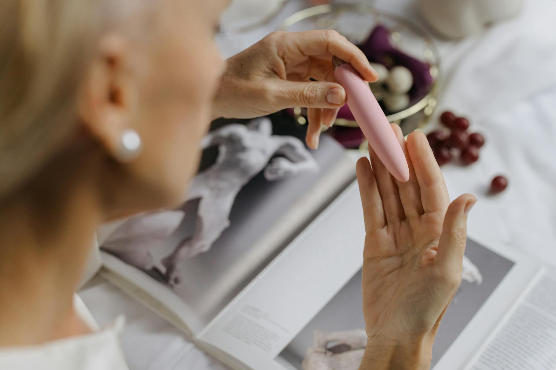 Close-up of hands holding a pink vibrator in an intimate setting, symbolizing personal pleasure and relationship trust.