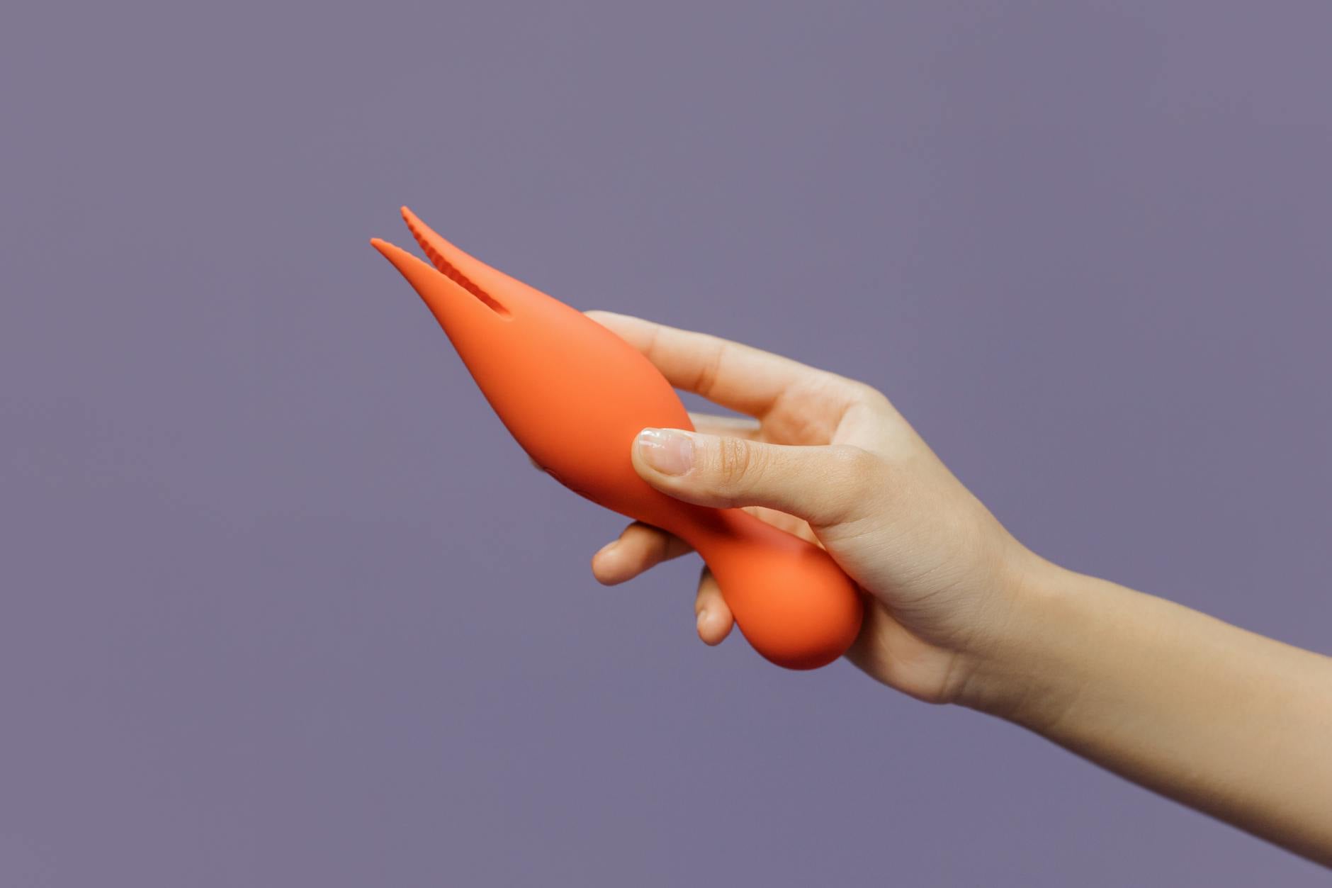 Close-up of a hand holding a lemon vibrator against a minimalistic purple backdrop, showcasing modern sensuality and pleasure