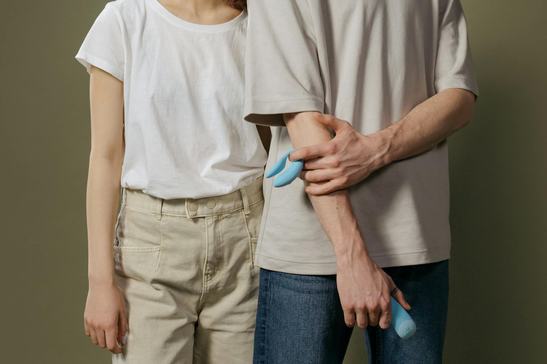 Hand holding an orange vibrator against a minimalistic backdrop, showcasing modern sensuality