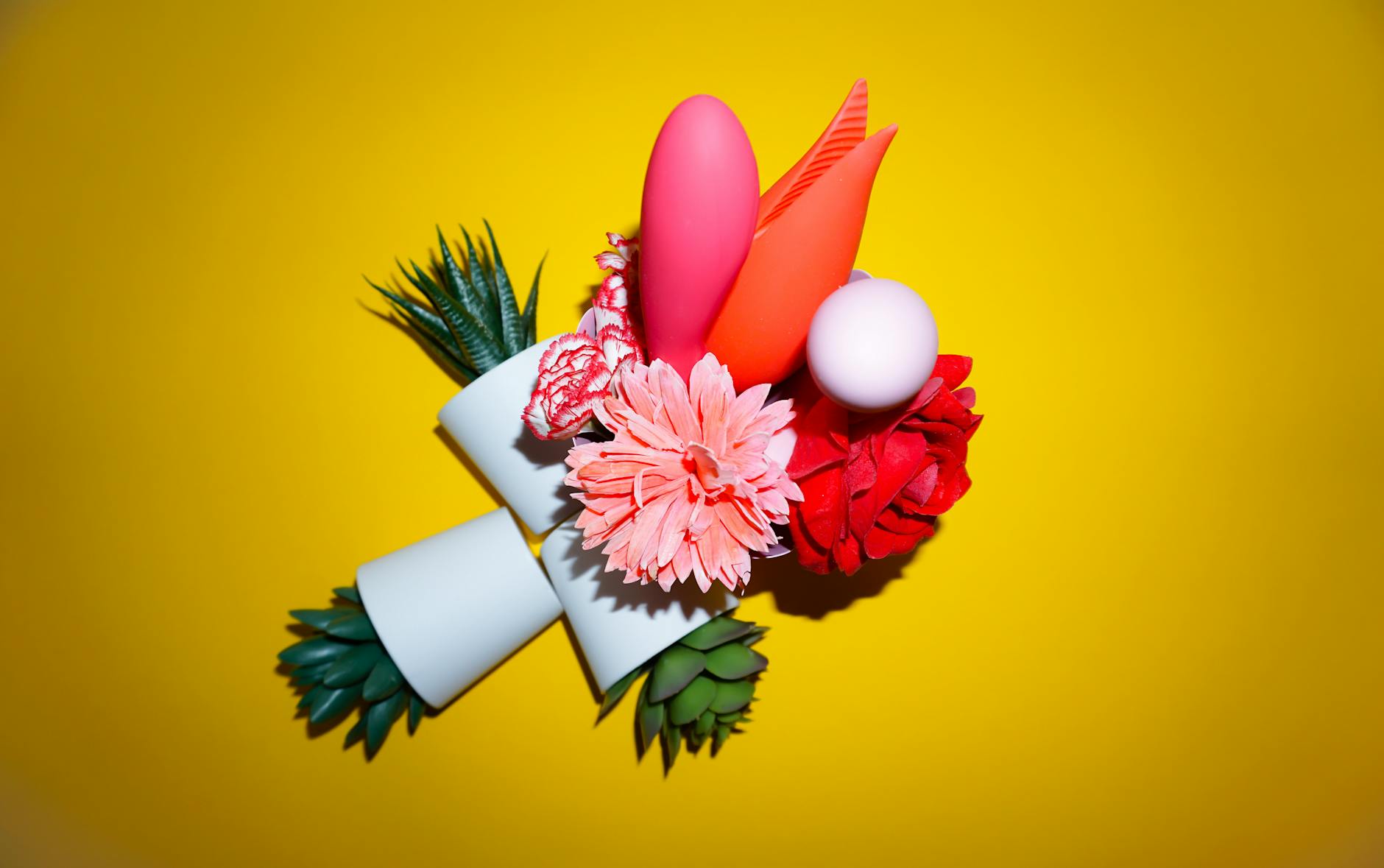 A blue clitoral vibrator surrounded by fresh lemons and citrus slices on a bright yellow studio background
